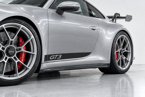 Illustrative mockup of a black GT3 lower door stripe on a silver Porsche 992 GT3, viewed from a close front oblique angle.